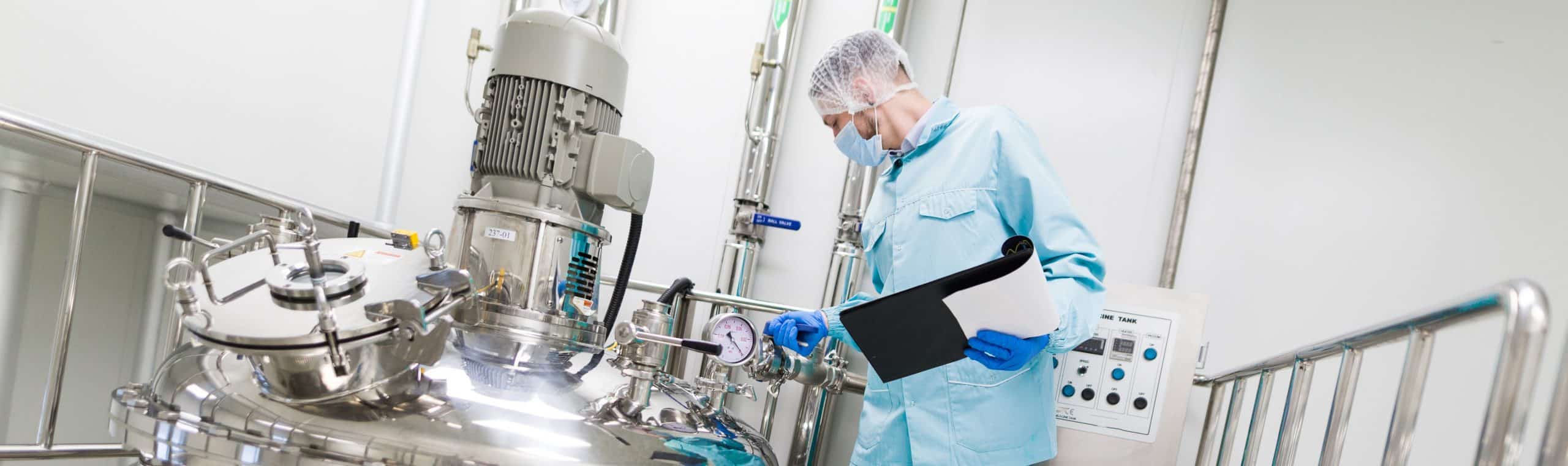 widescreen picture, scientist in blue lab suit and gas mask working with control panel, look at steel tank, check readings